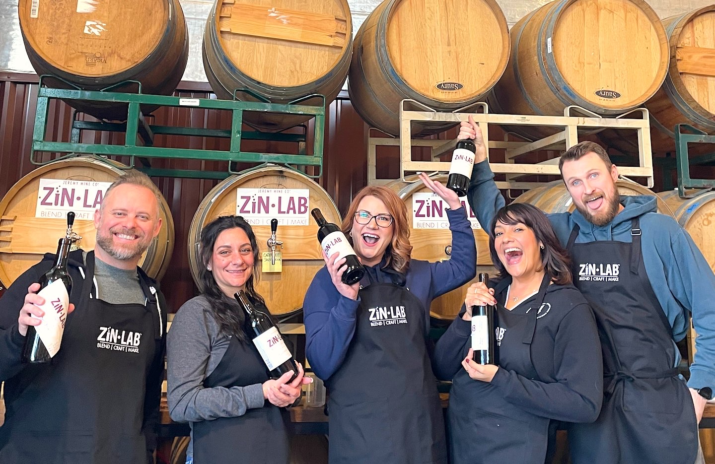 Zin Lab guests in the Lockeford barrel room holding the custom blends they bottled
