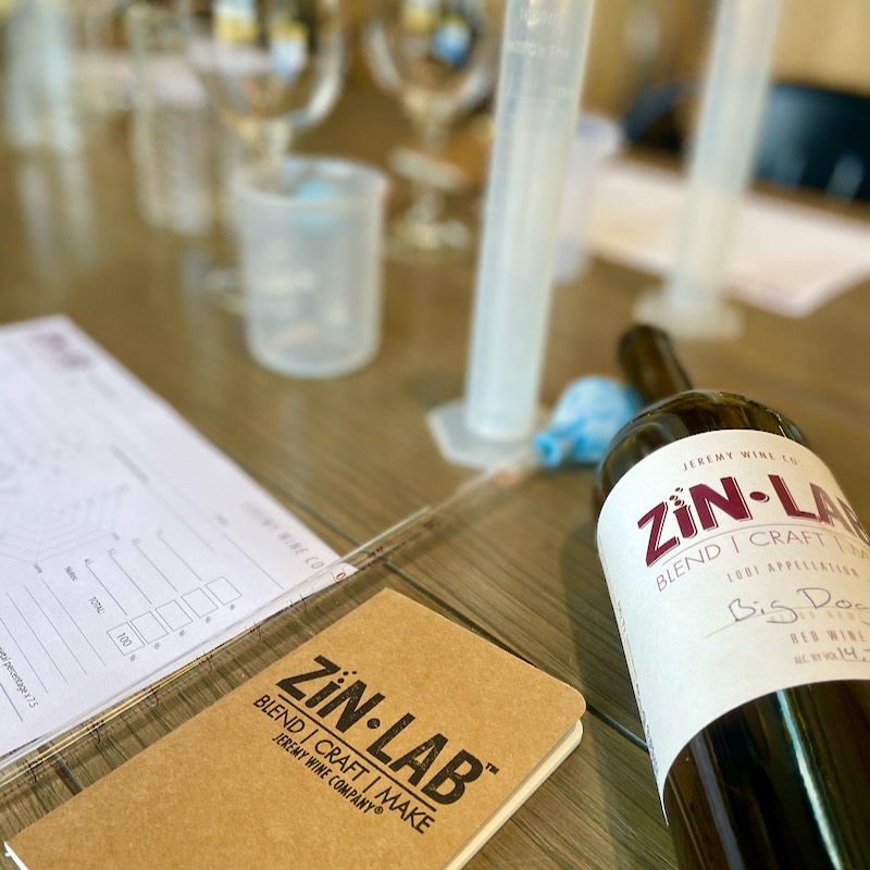 A Zin Lab blending station with graduated cylinders, tasting notes and a finished Zin Lab bottle